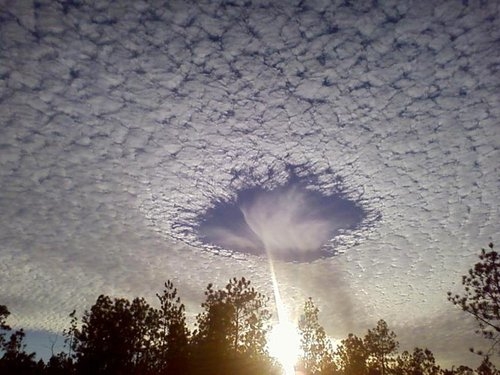 A rare meteorological phenomenon called a skypunch. Ice crystals form above the high-altitude cirro-cumulo-stratus clouds, then fall downward, punching a hole in the cloud.